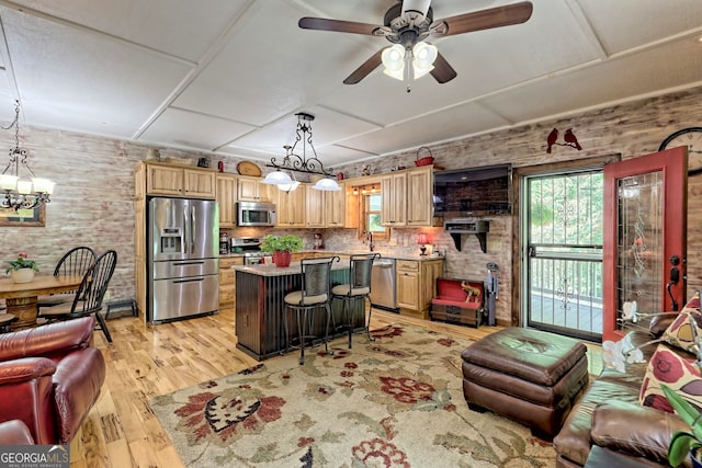 kitchen with open floor plan, a center island, stainless steel appliances, light wood-style floors, and light brown cabinets