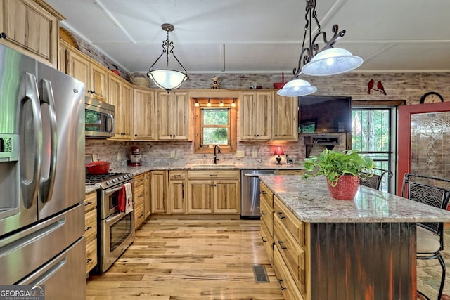 kitchen featuring appliances with stainless steel finishes, light brown cabinets, a sink, and light stone counters