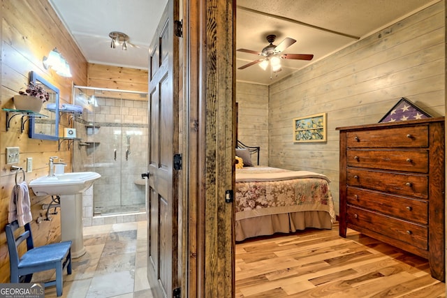 bedroom with a sink, wood walls, ensuite bath, and wood finished floors