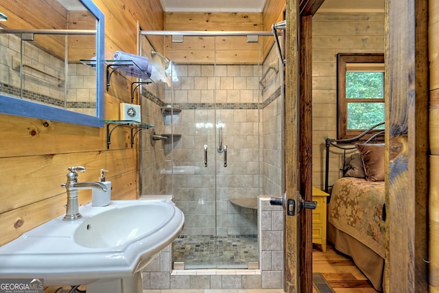 full bathroom with a stall shower, wooden walls, and a sink