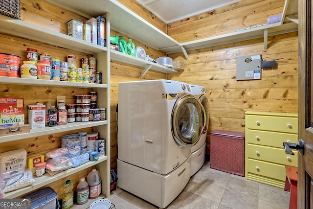 washroom with laundry area, wooden walls, and washing machine and clothes dryer