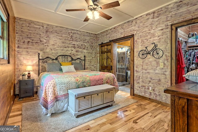 bedroom with ceiling fan, wooden walls, and wood finished floors