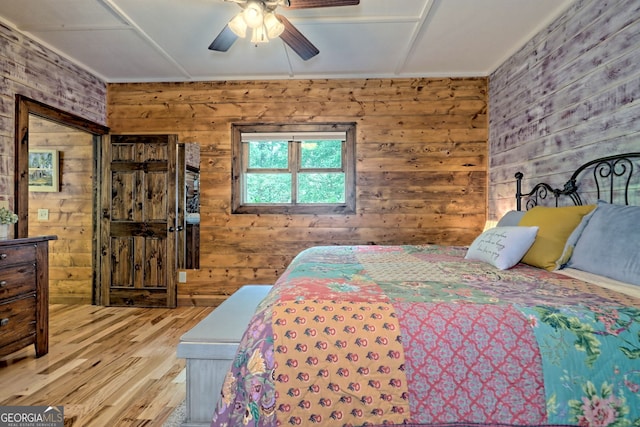 bedroom with ceiling fan, wooden walls, and wood finished floors