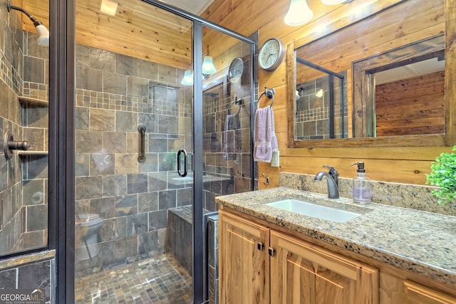 bathroom featuring wood walls, a shower stall, and vanity