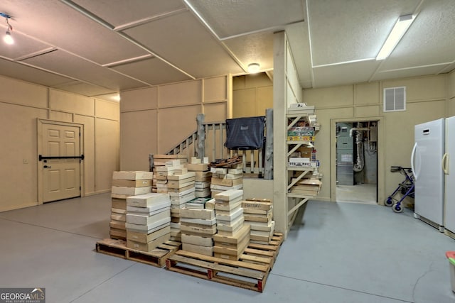 basement featuring freestanding refrigerator and visible vents