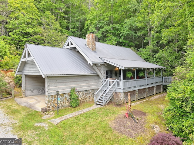 view of front facade with driveway, a chimney, a front lawn, and metal roof