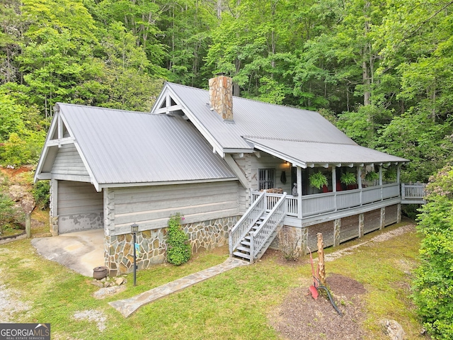 chalet / cabin with stairs, metal roof, a chimney, and a front yard