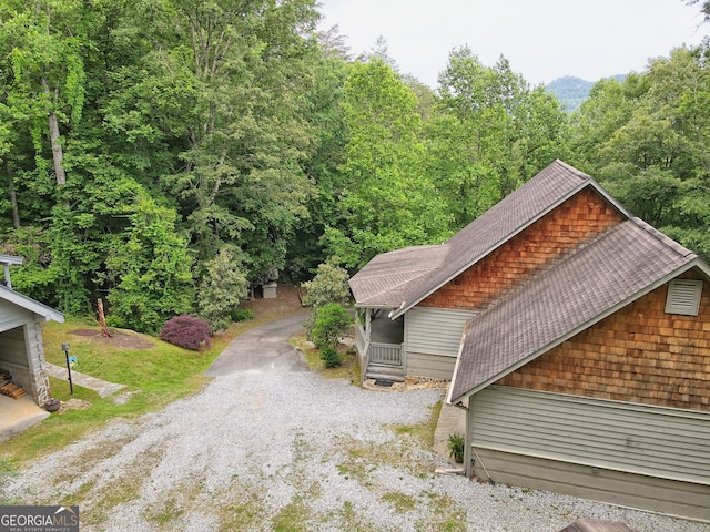 view of side of property with driveway and roof with shingles