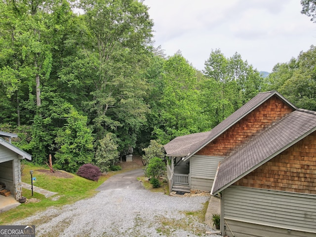 view of side of property featuring driveway and a shingled roof