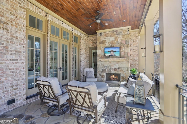 view of patio featuring french doors, an outdoor stone fireplace, and a ceiling fan