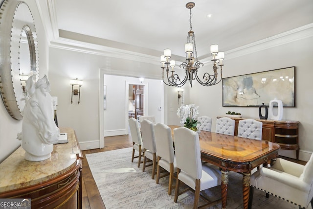 dining room with a notable chandelier, baseboards, ornamental molding, and wood finished floors