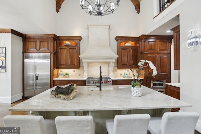 440 Belada Blvd, Sandy Springs, GA 30342 - kitchen with high quality appliances, custom range hood, a towering ceiling, a chandelier, and tasteful backsplash