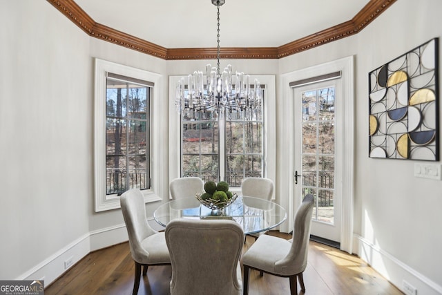 dining area featuring baseboards, ornamental molding, wood finished floors, and an inviting chandelier