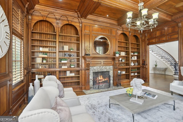 living room featuring built in features, coffered ceiling, wood ceiling, crown molding, and wood walls