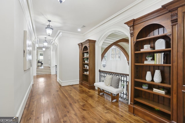 hallway with crown molding, arched walkways, dark wood finished floors, and baseboards