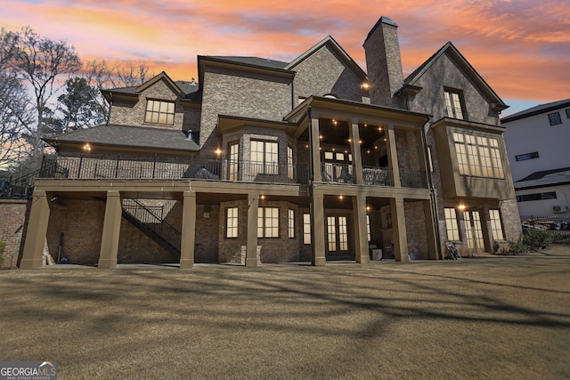 440 Belada Blvd, Sandy Springs, GA 30342 - back of property at dusk featuring french doors, a chimney, a balcony, stairs, and brick siding