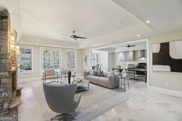 living area with recessed lighting, a ceiling fan, baseboards, french doors, and a raised ceiling