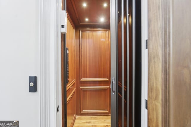 details with elevator, wood finished floors, and recessed lighting