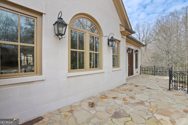 view of side of property with a patio, concrete block siding, and fence