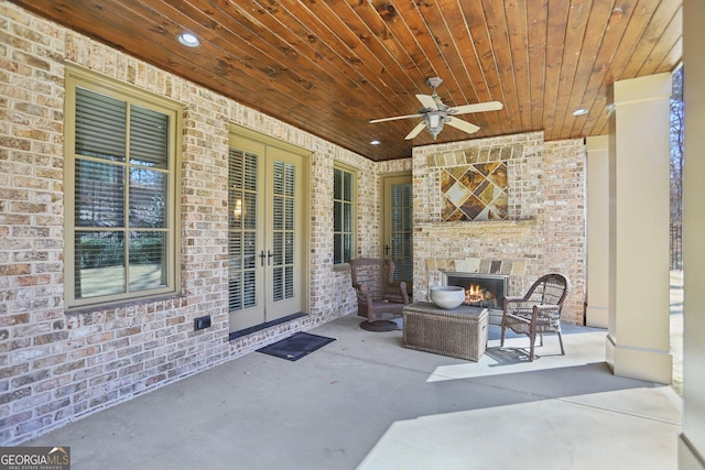 view of patio / terrace with an outdoor brick fireplace, a ceiling fan, and french doors