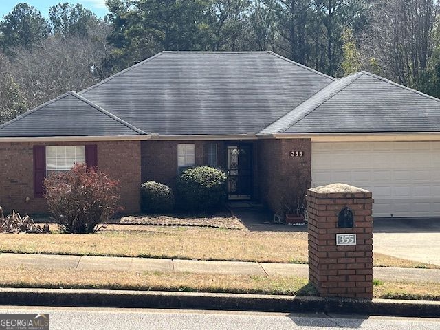 ranch-style house with a garage, brick siding, and a front yard