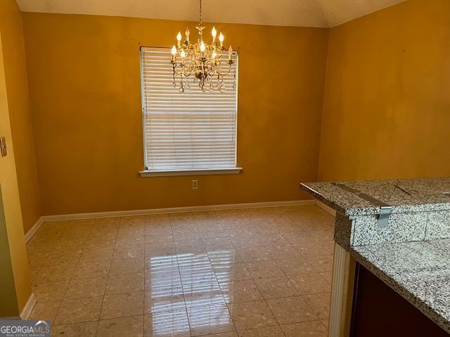 355 Tait Rd, Stockbridge, GA 30281 - unfurnished dining area with a chandelier, baseboards, and lofted ceiling