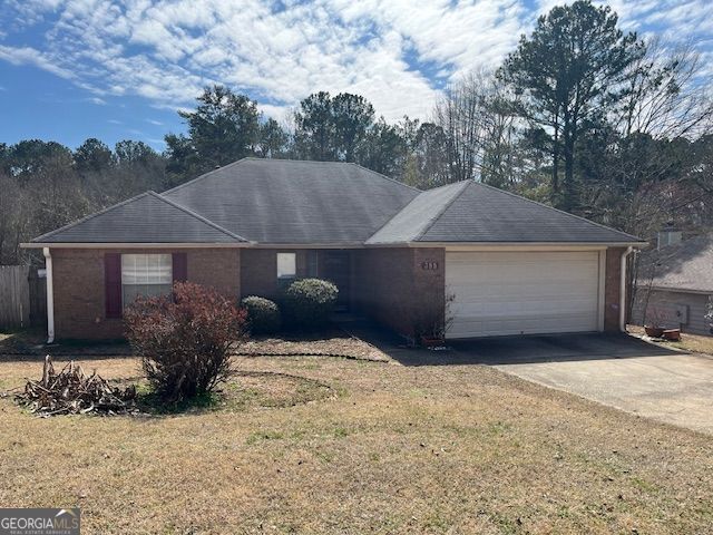 ranch-style home featuring an attached garage, brick siding, concrete driveway, and a front yard