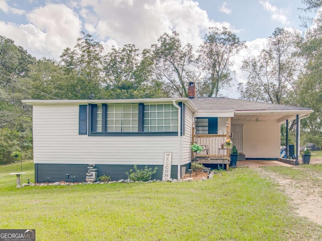 view of front of property featuring driveway, an attached carport, a chimney, and a front yard