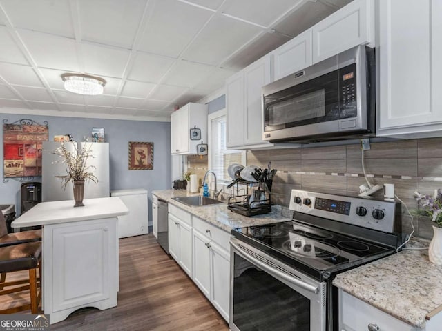 kitchen featuring dark wood finished floors, decorative backsplash, appliances with stainless steel finishes, white cabinetry, and a sink