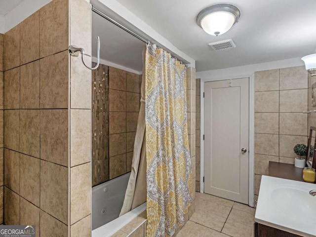 full bathroom with visible vents, tile patterned flooring, tiled shower / bath, vanity, and tile walls