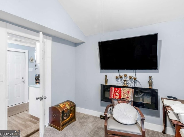 living area featuring light colored carpet, vaulted ceiling, and baseboards