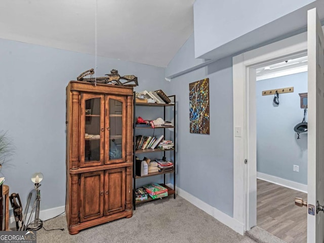 corridor with vaulted ceiling and baseboards