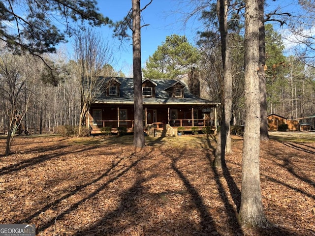 view of front facade with covered porch and a chimney