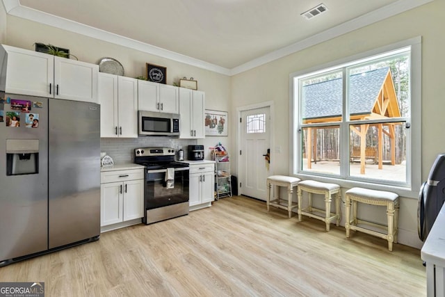 2634 Greenes Ln, Powder Springs, GA 30127 - kitchen featuring visible vents, light wood-type flooring, ornamental molding, decorative backsplash, and appliances with stainless steel finishes