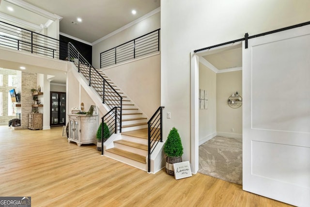 2634 Greenes Ln, Powder Springs, GA 30127 - stairs featuring ornamental molding, wood finished floors, a barn door, a high ceiling, and baseboards