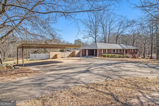 view of front facade with aphalt driveway, brick siding, fence, and a carport