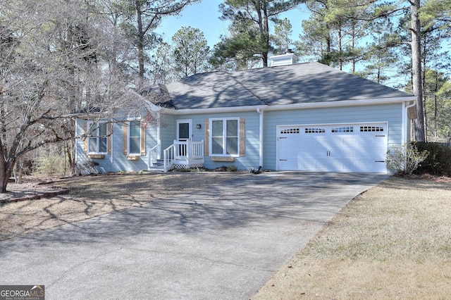 view of front of house with an attached garage, a chimney, concrete driveway, and roof with shingles