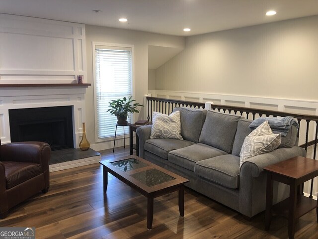 living room featuring a fireplace with raised hearth, dark wood-style flooring, and recessed lighting