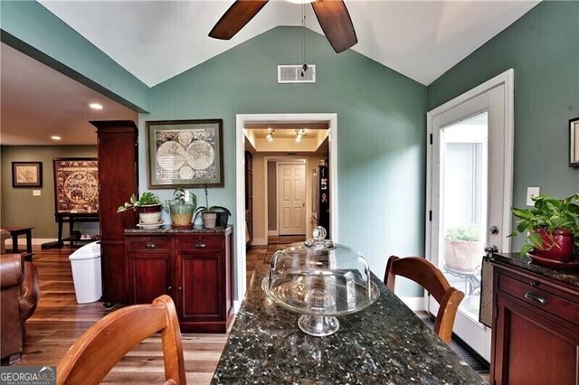 dining space featuring lofted ceiling, a ceiling fan, baseboards, visible vents, and light wood-style floors