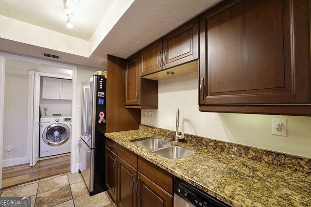 kitchen with washer / clothes dryer, visible vents, appliances with stainless steel finishes, a sink, and dark stone counters