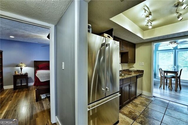 kitchen featuring a textured ceiling, ceiling fan, baseboards, appliances with stainless steel finishes, and track lighting