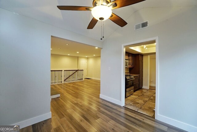 unfurnished room with lofted ceiling, visible vents, baseboards, and wood finished floors