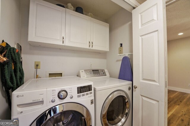 washroom featuring cabinet space, baseboards, washer and dryer, and wood finished floors