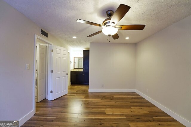 unfurnished room with dark wood-style floors, a textured ceiling, visible vents, and baseboards