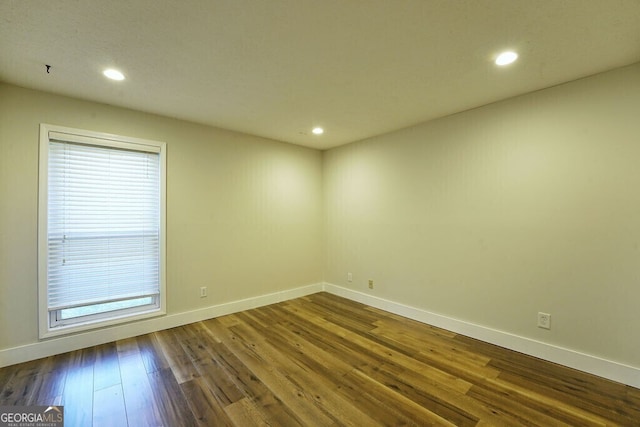 empty room featuring recessed lighting, dark wood finished floors, and baseboards