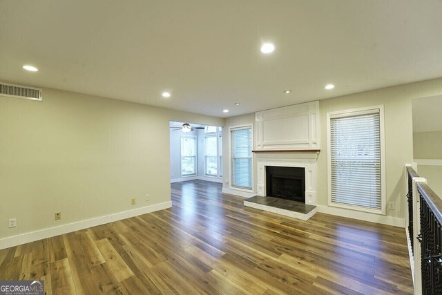 unfurnished living room with recessed lighting, a large fireplace, visible vents, and wood finished floors