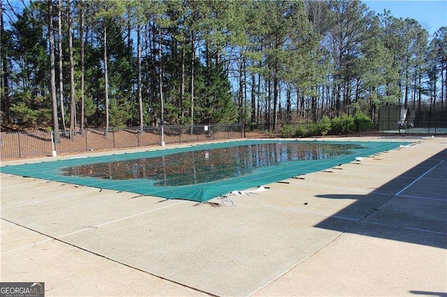 community pool with a patio area and fence