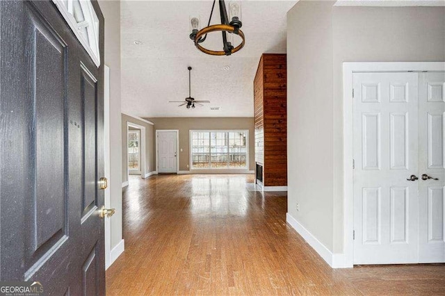 foyer entrance featuring ceiling fan, a textured ceiling, baseboards, and wood finished floors