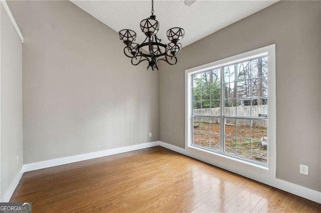 unfurnished dining area with baseboards, a chandelier, and wood finished floors