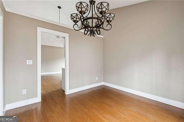 unfurnished dining area featuring baseboards, wood finished floors, and an inviting chandelier